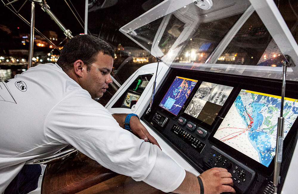 captain operating electronics at the helm of a sport-fisher