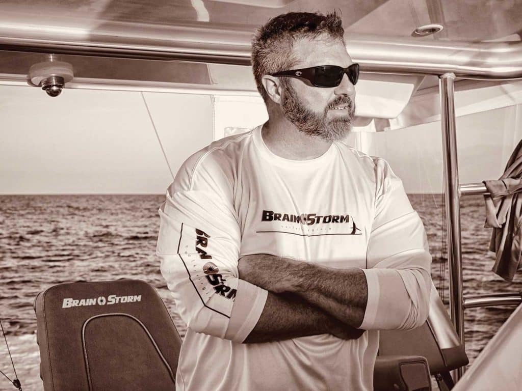 A black and white photo of a boat captain at the helm.