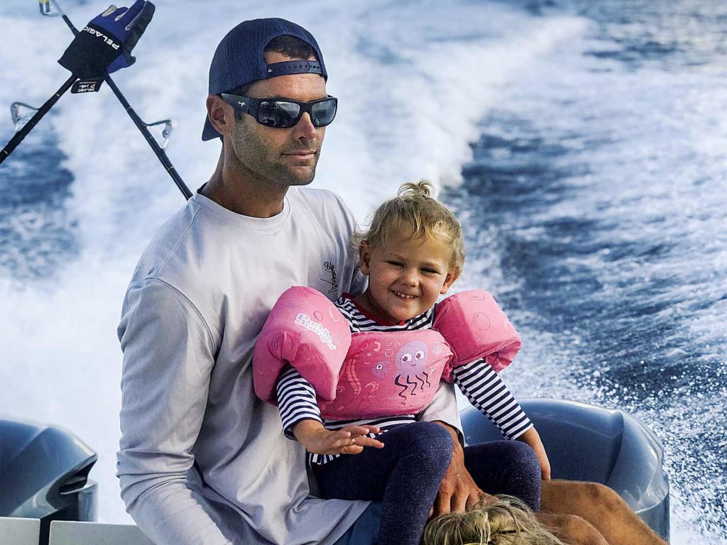 man in sunglasses and cap with daugher in his lap