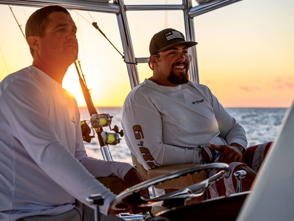 two men behind the helm of a boat