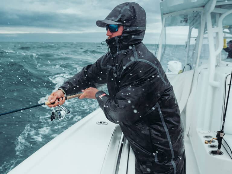 An angler fishing in foul weather conditions while wearing Columbia PFG Force XII Jacket.