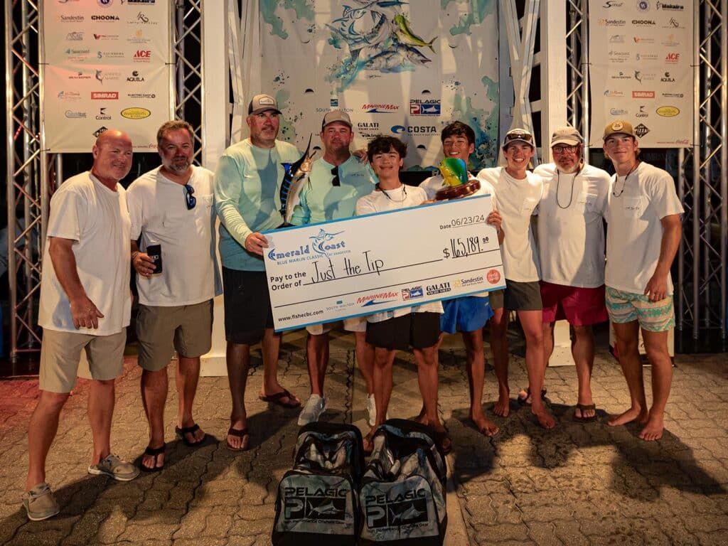A sport-fishing team celebrates at the Emerald Coast Blue Marlin Classic awards ceremony. They hold up an oversided check