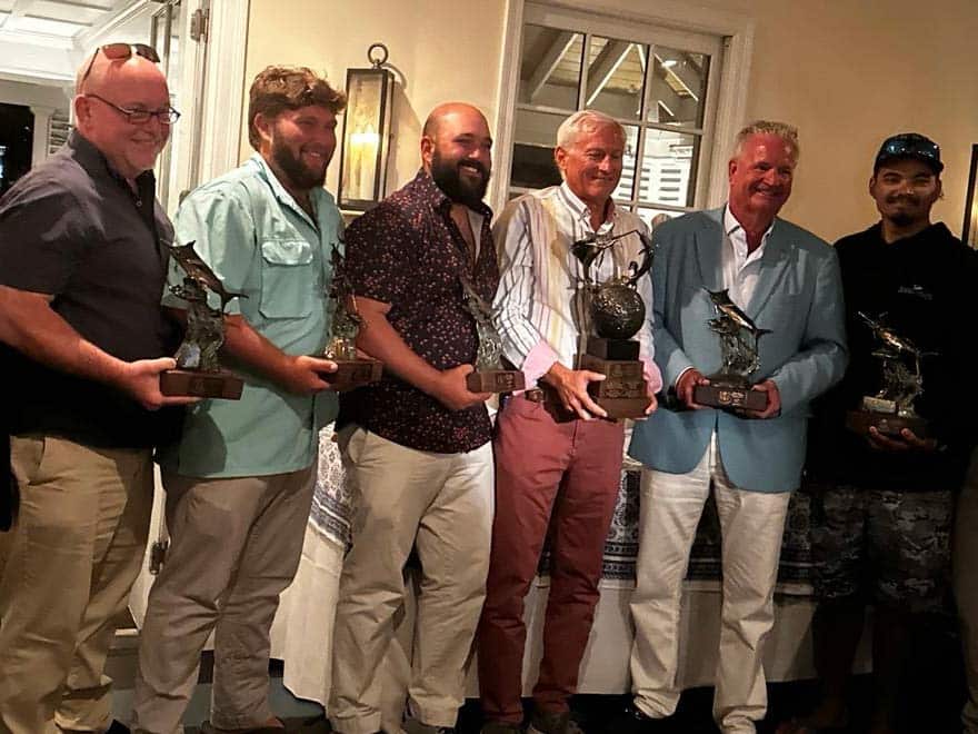 Six anglers holding up sport-fishing trophies.