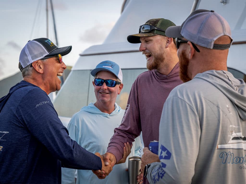 A group of men shake hands and laugh while attending the Scrub Island Billfish Series.