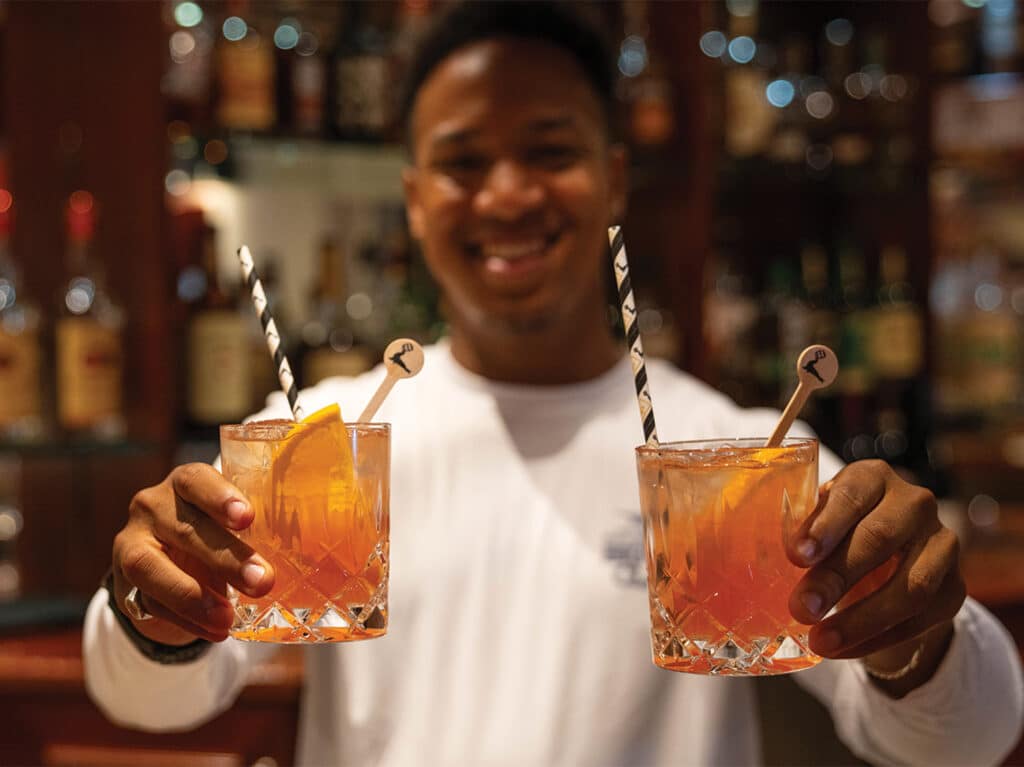 A bartender holding up two Gosling Rum Swizzles.