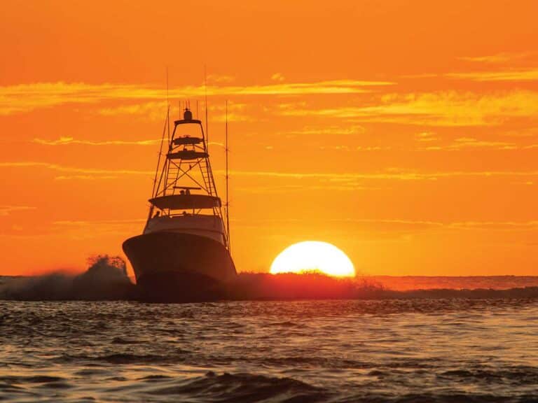 Silhouette of a sport-fishing boat cruising across the open water.