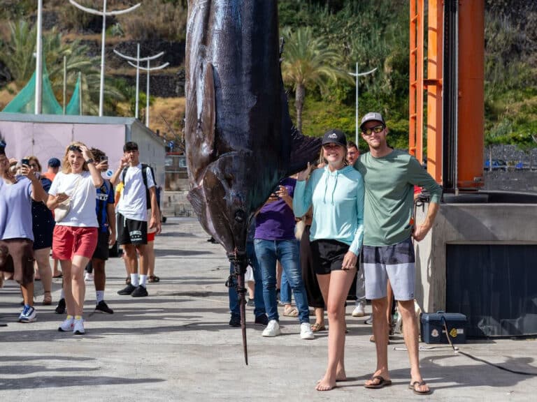 A woman stands next to her husband and a large grander marlin caught off the coasts of Madeira.