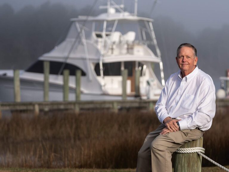 Randy Ramsey in front of a scenic view with a sport-fishing boat in the background.