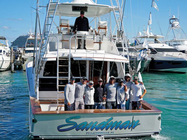 Team Sandman stand in celebratin in the cockpit of a sport-fishing boat docked in the marina.