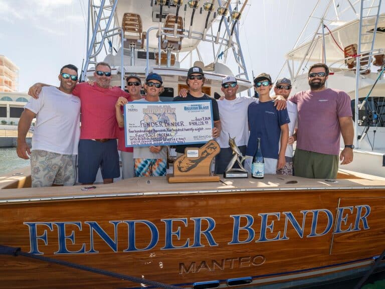 A sport-fishing team standing in celebration in the cockpit of a sport-fishing boat. The two center anglers are holding up a large over-sized check.