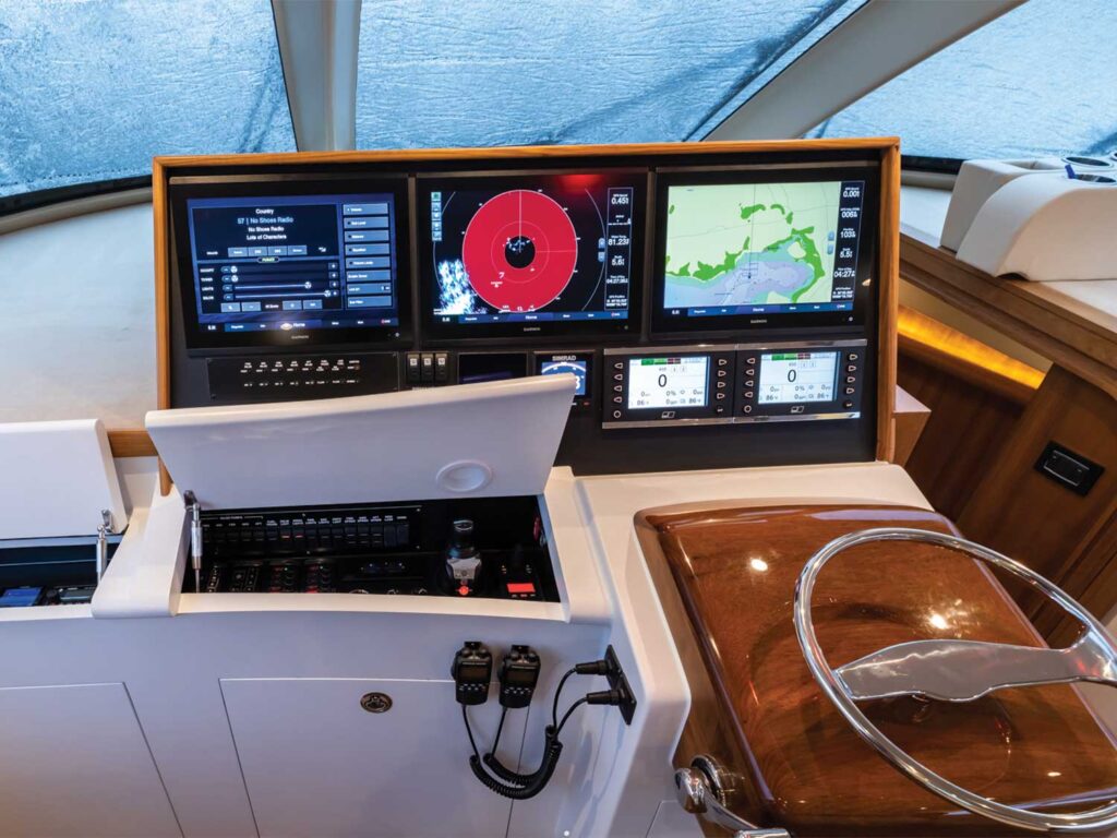 Detail shot of the helm of a sport-fishing boat. The panel includes digital displays for navigation, depth, and sonar. A radio is installed to the left of the steering wheel.