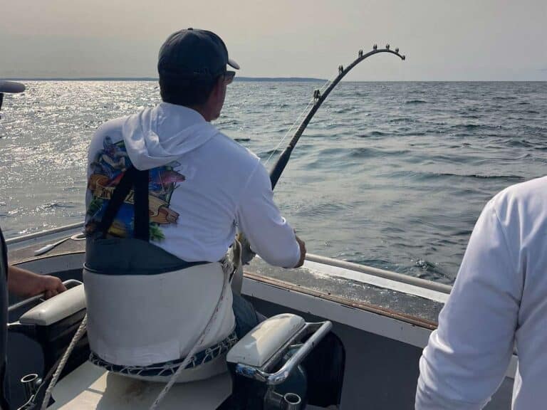 a man sitting on a boat with a fishing pole