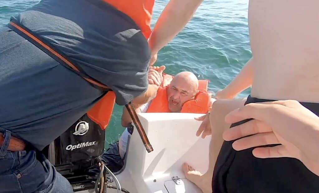 man in life jacket pulled aboard.