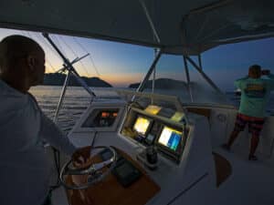 A boat captain navigating a sport-fishing boat through low-light conditions.