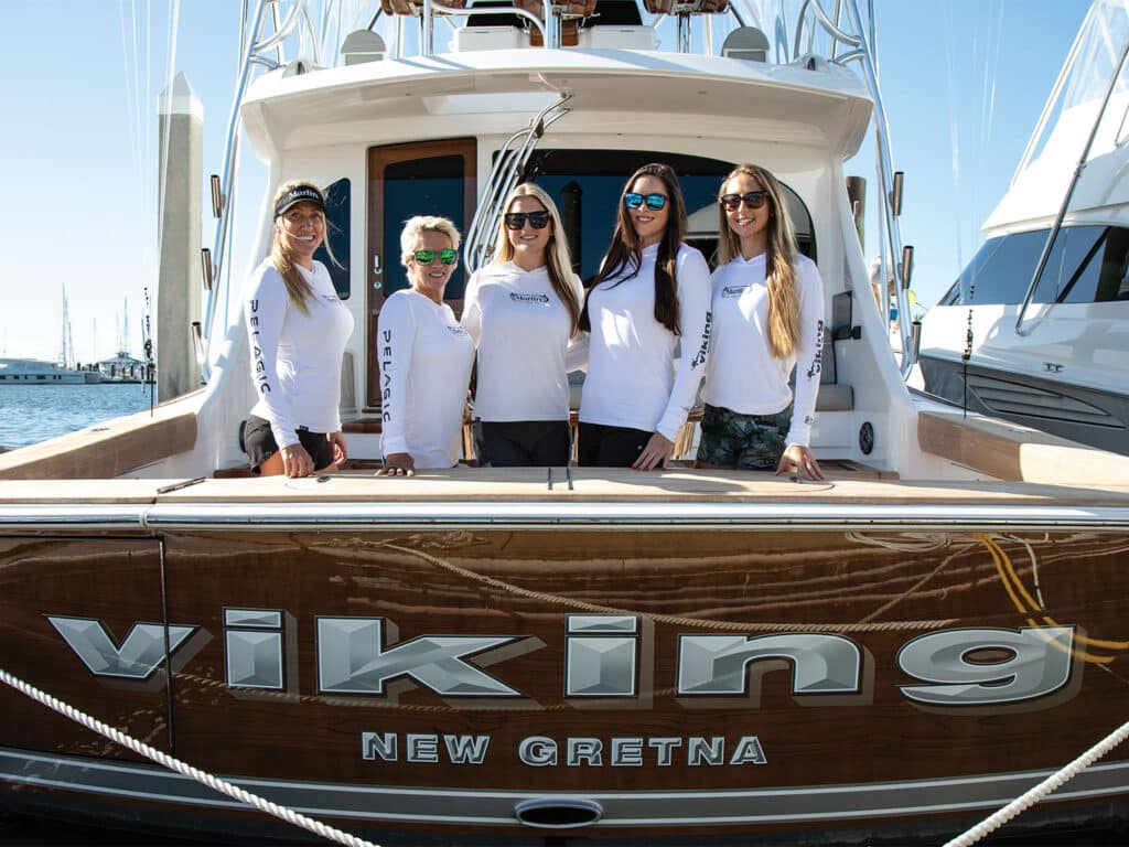 A group of women stand in the cockpit of a sport-fishing boat.