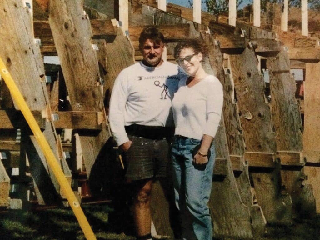 Russ Garufi stands next to his wife Linda on a boat-building site.