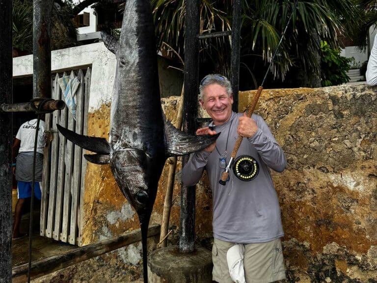 Angler poses with large swordfish fly tackle record at a weigh-in station.