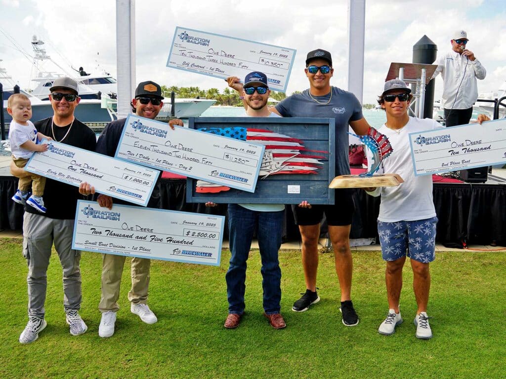 Team Owe Deere stand at the awards ceremony holding oversized checks.