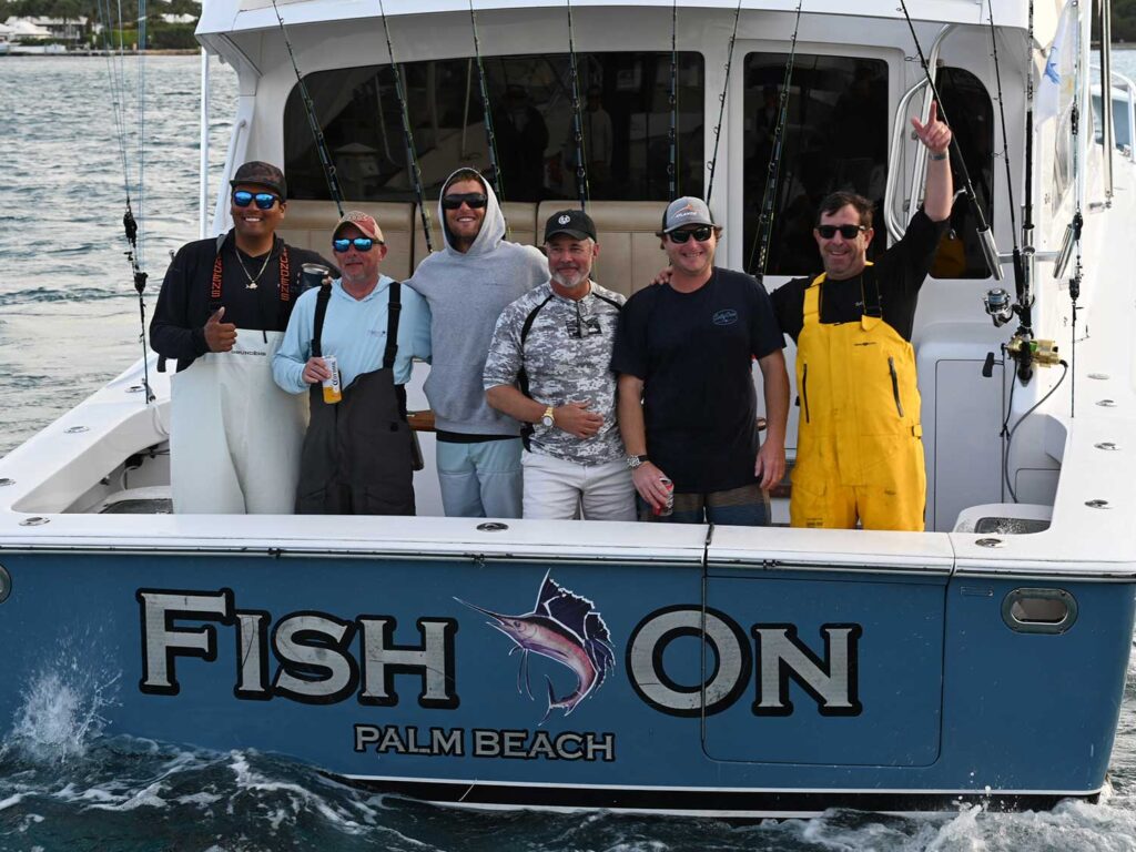 A team of sport-fishing anglers stand in the transom of their sport-fishing boat.