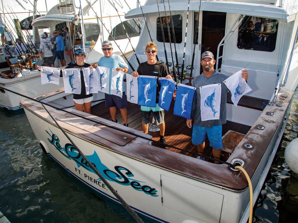 A team celebrating in their cockpit while holding marlin release flags.